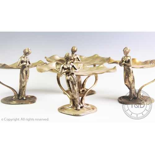 95 - A set of four silver plated Art Nouveau figural table centres, each modelled as raised twin lily pad... 