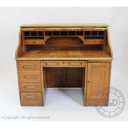 950 - An Edwardian golden oak roll top desk, with tambour front over five drawers and a cupboard door 115c... 