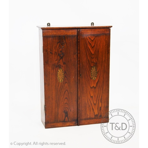 956 - An Edwardian stained ash wall hanging tool cabinet, the two doors centred with an oval fan, enclosin... 