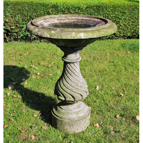 969 - A reconstituted stone bird bath, of baluster form with incised spiral detail set on a plinth base, 8... 