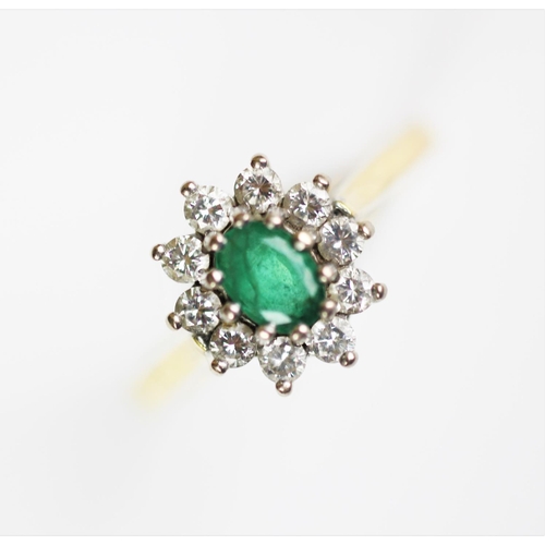 260 - An emerald and diamond oval cluster ring, the central oval emerald claw set within a surround of ten... 