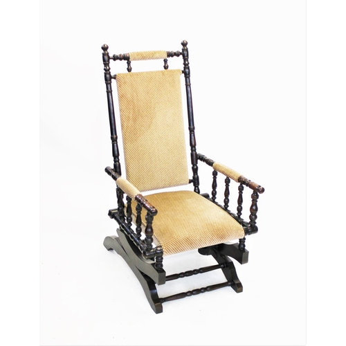 941 - A late 19th century American walnut rocking chair, with a padded back and seat raised upon turned up... 