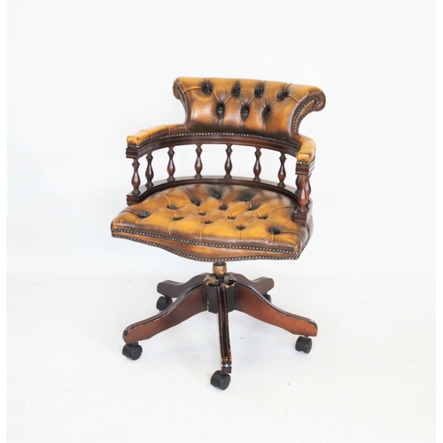 963 - A tan leather revolving captains chair, 20th century, with a button back, padded serpentine seat on ... 