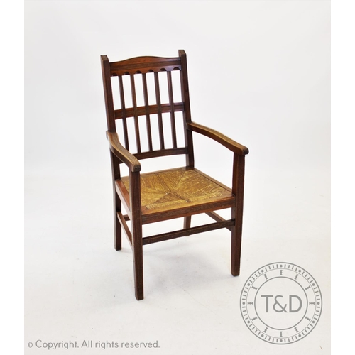 801 - An Edwardian Arts and Crafts walnut elbow chair, with an angular rail back above reeded arms and an ... 