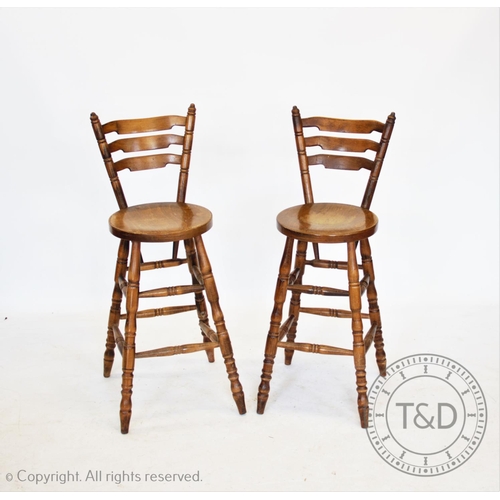 837 - A set of four stained beech wood bar stools, each with a graduated ladder back, circular seat on tur... 