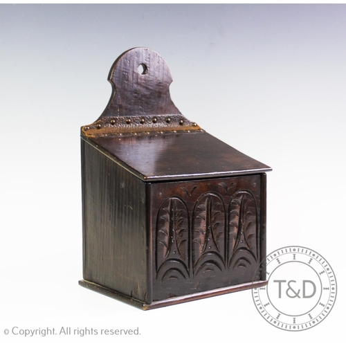 438 - A 19th century carved oak candle box, the rectangular cover hinged by a leather strap above a front ... 