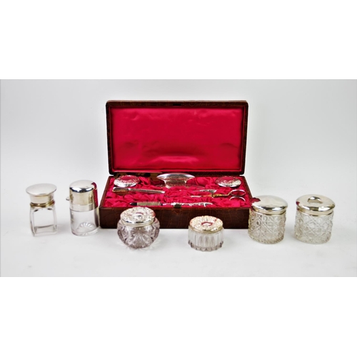 27 - An Edwardian harlequin silver backed manicure set, comprising: two silver topped glass jars, brush, ... 