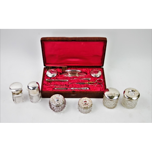 27 - An Edwardian harlequin silver backed manicure set, comprising: two silver topped glass jars, brush, ... 