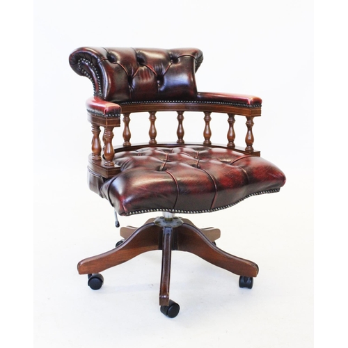 830 - An oak framed blood red leather upholstered captains chair, late 20th century, with a button back pa... 