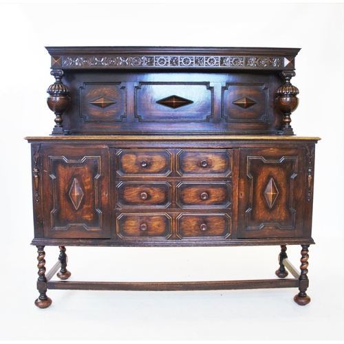 838 - A 1930's oak Jacobean revival sideboard, the raised back flanked by carved bulbous uprights, above t... 