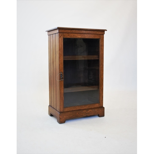 848 - An Edwardian oak music cabinet, the rectangular moulded top above a single glazed door, enclosing tw... 