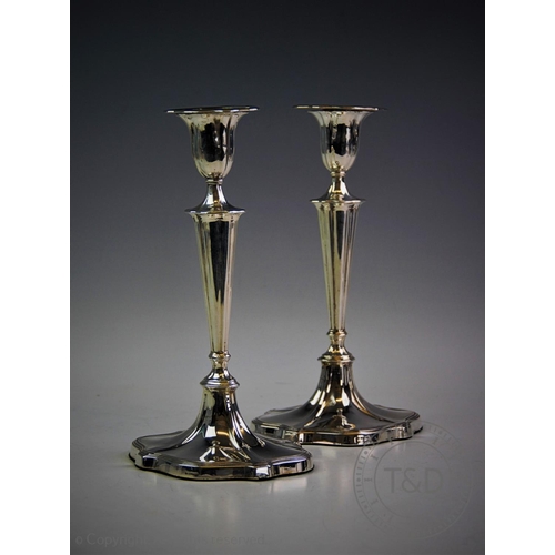 23 - A pair of Edwardian silver candlesticks, Sheffield 1906, each modelled on a tapering base, supportin... 