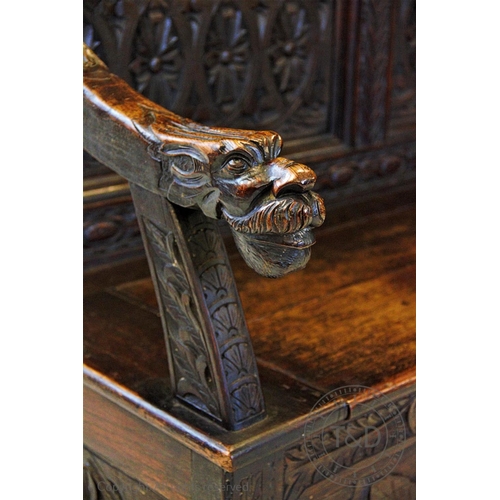 813 - A 19th century carved oak high back settle, circa 1870, with a twin dragon mask pediment above a pan... 