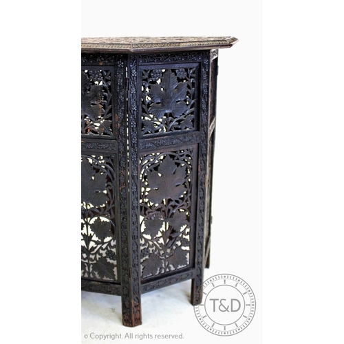 853 - An early 20th century Anglo Indian carved hardwood  table, the ebonised octagonal top carved in reli... 