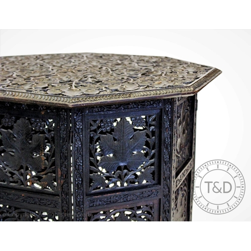 853 - An early 20th century Anglo Indian carved hardwood  table, the ebonised octagonal top carved in reli... 