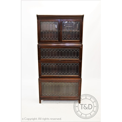 865 - A 1930's Gunn walnut stacking bookcase, with a pair of leaded glazed doors above three tiers each wi... 