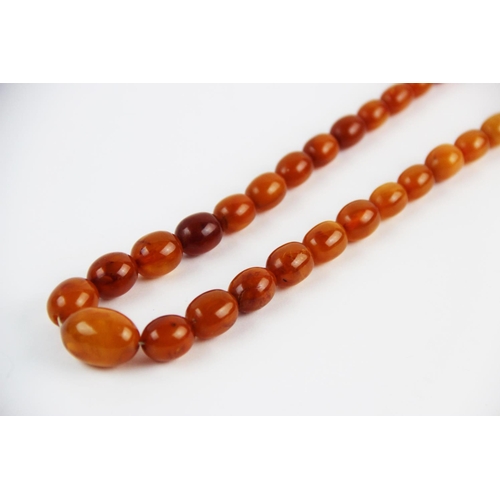 134 - A 'Butterscotch' amber single strand bead necklace, the sixty-nine graduated beads (largest measurin... 