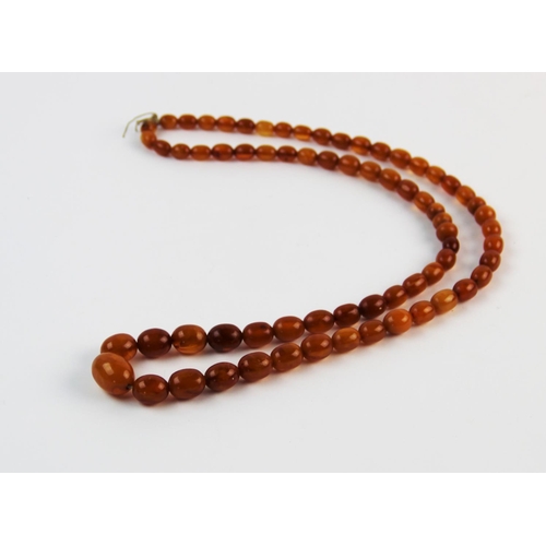 134 - A 'Butterscotch' amber single strand bead necklace, the sixty-nine graduated beads (largest measurin... 