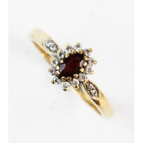 186 - A garnet and white stone cluster ring, the central mixed cut oval garnet with a border surround of w... 