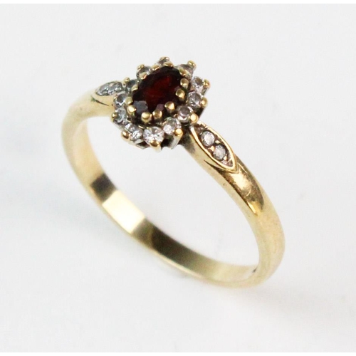 186 - A garnet and white stone cluster ring, the central mixed cut oval garnet with a border surround of w... 