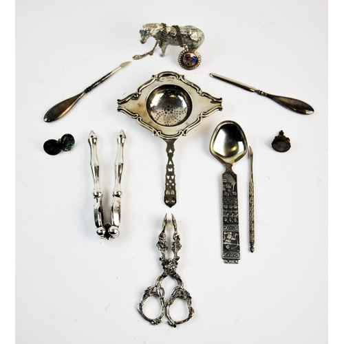 41 - A selection of silver and silver coloured items, to include, a George V silver tea strainer, George ... 