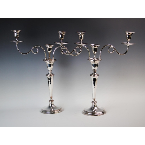 82 - A pair of early 20th century silver plated three branch candelabras, each with two stylised curling ... 