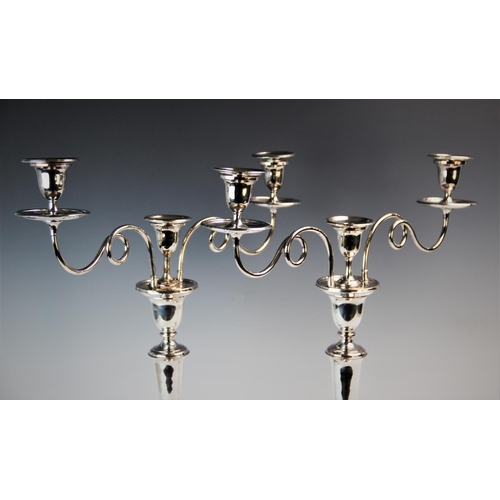 82 - A pair of early 20th century silver plated three branch candelabras, each with two stylised curling ... 