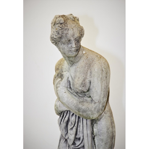 930 - A reconstituted stone garden statue, modelled as a scantily clad classical female figure, upon a cir... 