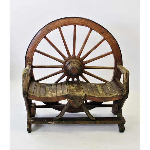 931 - A rustic cart wheel garden bench, the back constructed from a wooden cart wheel with an iron rim, ab... 