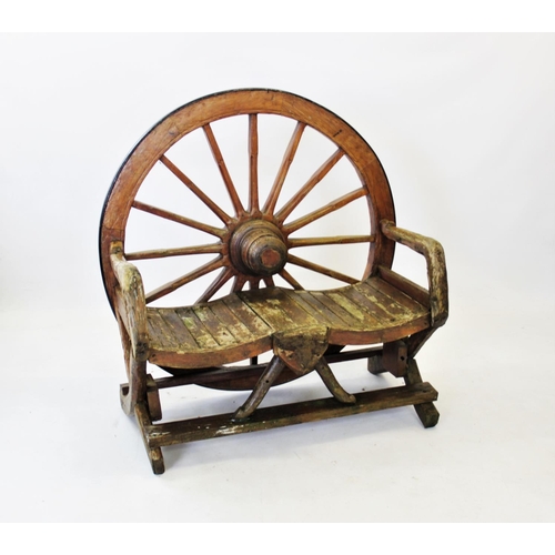 931 - A rustic cart wheel garden bench, the back constructed from a wooden cart wheel with an iron rim, ab... 