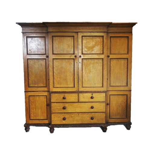 888 - A 19th century scumbled pine breakfront wardrobe, with an over hanging cornice above a central pair ... 