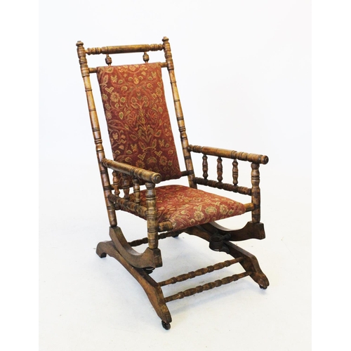 895 - An American stained beech wood rocking chair, with a padded back and seat, raised upon a ring turned... 