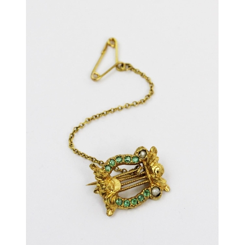 172 - An emerald and seed pearl set lyre form brooch, all set in yellow metal, unmarked, attached safety c... 