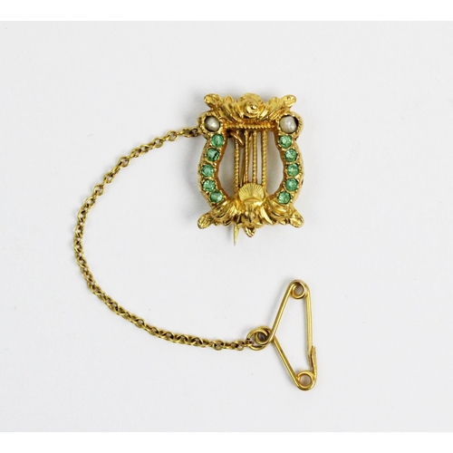 172 - An emerald and seed pearl set lyre form brooch, all set in yellow metal, unmarked, attached safety c... 