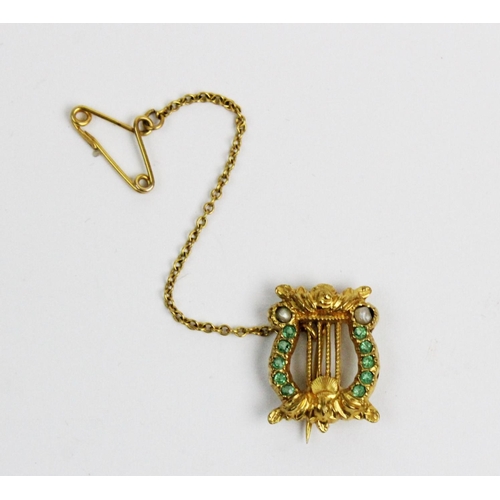 172 - An emerald and seed pearl set lyre form brooch, all set in yellow metal, unmarked, attached safety c... 