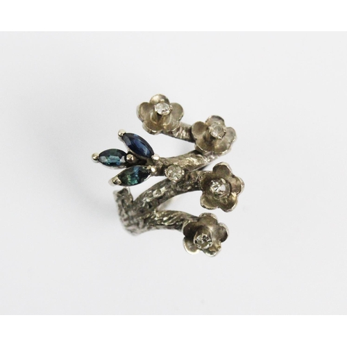 179 - A diamond and sapphire abstract floral ring, designed as a blossoming branch issuing four diamond se... 