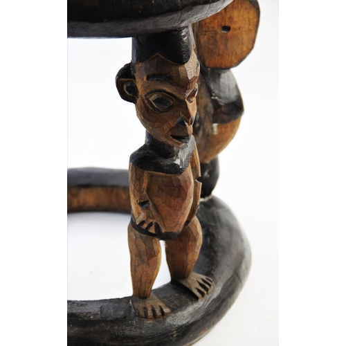 408 - A Nigerian Yoruba tribal stool, of circular form, designed with four figural legs, alternating Ibeji... 