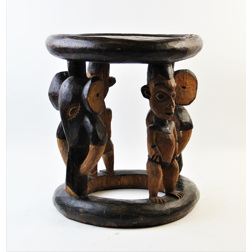 408 - A Nigerian Yoruba tribal stool, of circular form, designed with four figural legs, alternating Ibeji... 