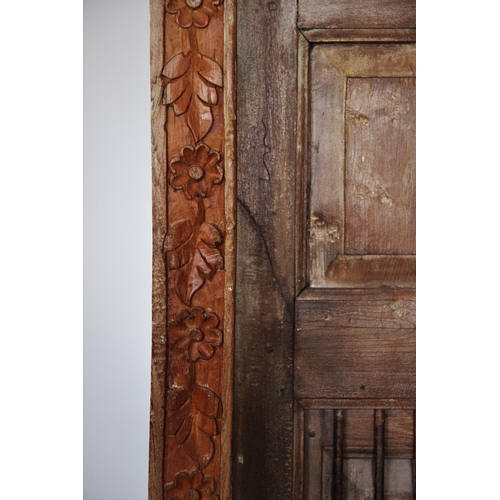 423 - A Rajasthani rustic hardwood balcony door, with an iron bar grille above a pair of panelled doors, w... 