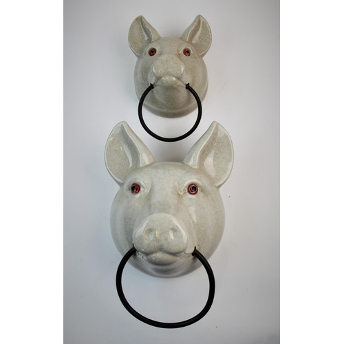 501 - A graduated pair of continental ceramic towel rails, 20th century, modelled as pig masks, the craque... 