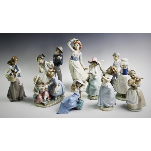 505 - A Lladro figure of a girl holding a basket with three puppies, a Nao group, a young dancing couple, ... 