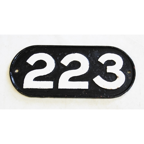 548 - A vintage cast iron railway locomotive number plate, of oval form, the cast numbers '223' painted in... 