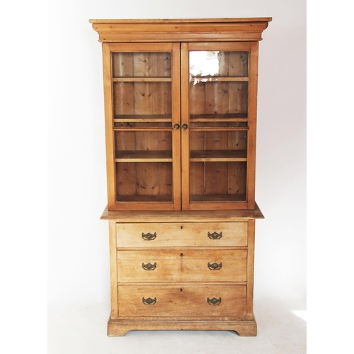 706 - A Victorian pine bookcase on chest, with a moulded cornice above a pair of glazed doors enclosing th... 