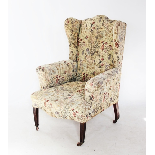 745 - An Edwardian wing back armchair, the arched padded back with out swept wing back and arms, over a se... 