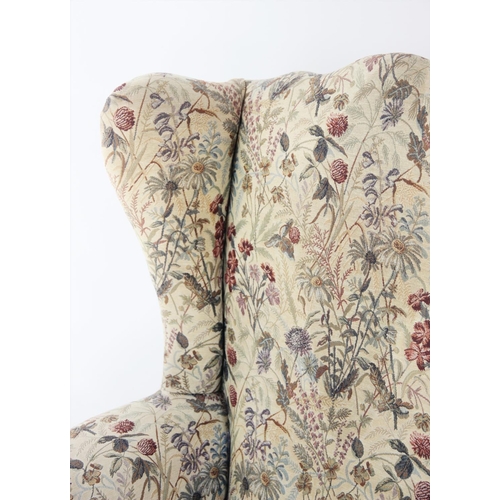 745 - An Edwardian wing back armchair, the arched padded back with out swept wing back and arms, over a se... 