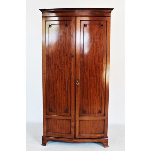 765 - An Edwardian mahogany bow front wardrobe, with a moulded cornice above a pair of doors applied with ... 