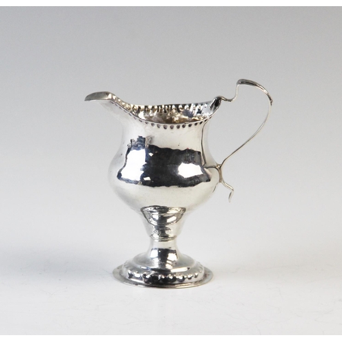 111 - A George III silver milk jug, London 1780, of plain polished, pedestal form, with beaded rims and sc... 