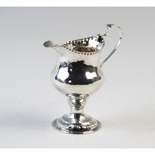 111 - A George III silver milk jug, London 1780, of plain polished, pedestal form, with beaded rims and sc... 