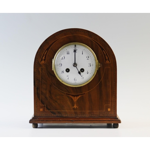 364A - An Edwardian walnut mantel clock, of arched form with a 10cm white enamelled dial and two train move... 