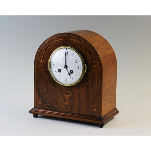 364A - An Edwardian walnut mantel clock, of arched form with a 10cm white enamelled dial and two train move... 